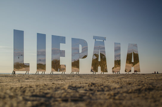 Liepaja city title at Baltic beach. Big mirroring letters in sunny evening. 