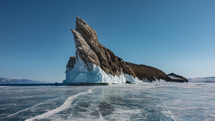 A picturesque rocky island devoid of vegetation rises in the middle of a frozen lake. Bizarre...