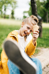 Portrait of a funny blonde teenage girl with ice cream on a walk in the park. Child outdoors