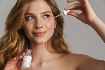Half-naked white ginger woman applying face serum