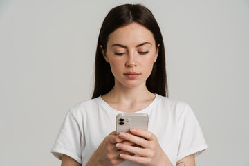 Young brunette woman in t-shirt using mobile phone