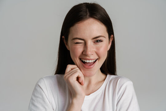 Young brunette woman winking and laughing at camera