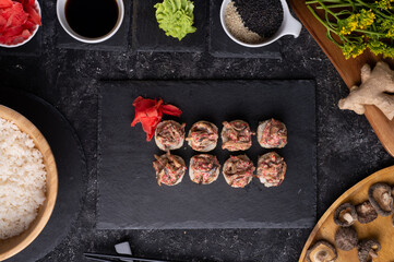 sushi roll  with shiitake mushrooms  served  at black dish with rise at black table. flat lay