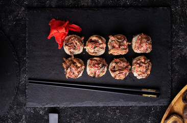sushi roll  with shiitake mushrooms  served  at black dish  at black table. flat lay