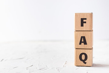 Wooden cubes with text FAQ on white putty texture background. Frequently asked questions. Flat lay,...