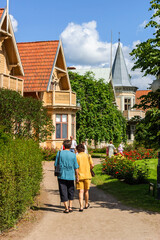 Fototapeta na wymiar People walking in a park with old houses in the city Hjo in Sweden