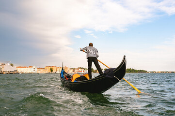 Unrecognizable gondolier man rowing in Venice channels. - obrazy, fototapety, plakaty