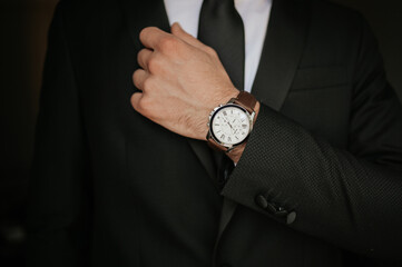 Unrecognizable businessman in suit showing a watch.