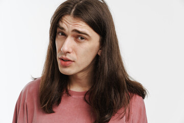 Young confused man with long hair posing and looking at camera