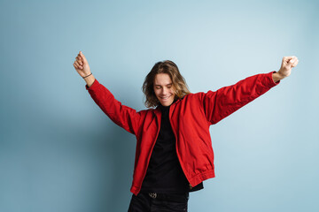 Young white man wearing red jacket smiling and dancing on camera