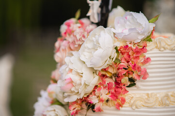 Wedding cake with flowers decoration and couple on the top.