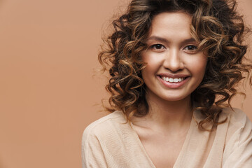 Young curly hispanic woman smiling and looking at camera