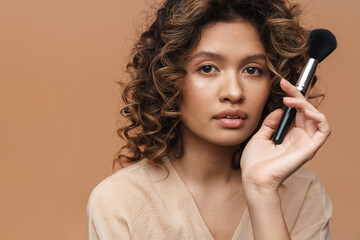 Obraz premium Young curly hispanic woman posing with powder brush