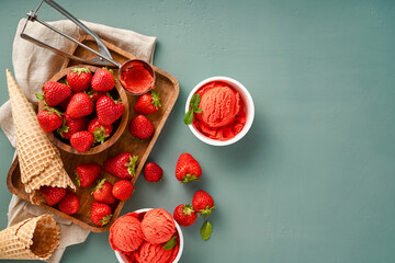 Strawberry sorbet with strawberries on blue background with copy space. Heap of strawberry with ice cream in ice cream paper cups.