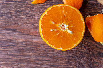 Fresh orange fruit and orange fruit cut in half on a wooden table