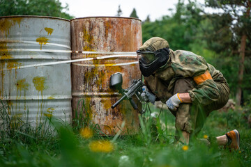 A player with rifle behind cover on a paintball battlefield