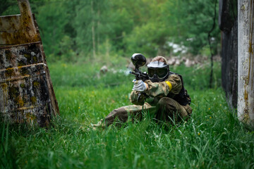 The player shoots a gun on the battlefield in a paintball - obrazy, fototapety, plakaty