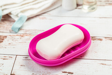 soap on pink plastic soap dish with towels on white wooden table in bathroom