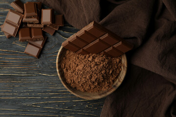 Tasty chocolate bars and powder on wooden table