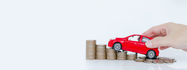 Businessman and close up hand holding model of toy car red on over a lot money of stacked coins -...