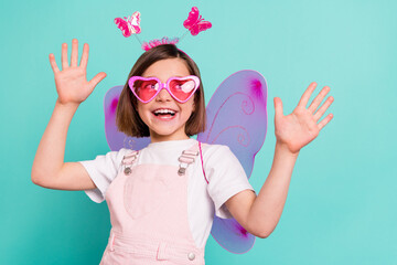 Photo of funny charming schoolgirl dressed pink overall wings dancing looking empty space isolated...