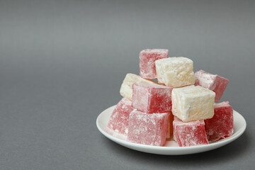 Plate with delicious turkish delight on gray background