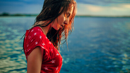 woman in a red wet dress at sunset near a pond