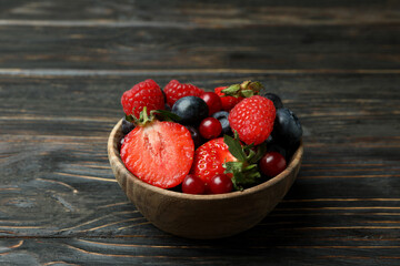 Bowl with berry mix on wooden background