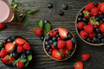 Bowls with berry mix and juice on wooden background