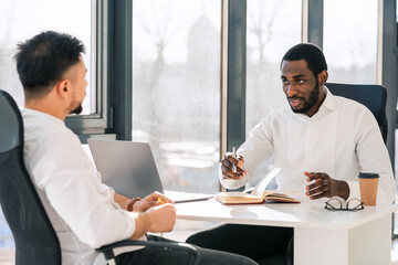 Business colleagues talking while sitting at the table in the office