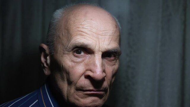 Large scale portrait of angry sullen aged man who turn about face standing at home in dark room