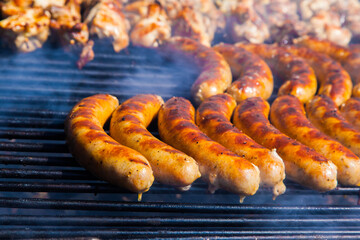 Sausages and meat on a wooden skewers on the grill, close-up.