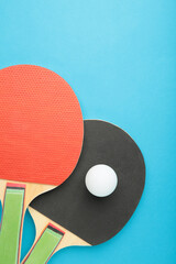 Ping pong rackets and ball on blue background