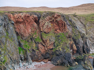 Striking mixes of different grey and red rock types in the coastal cliffs on the Ness of Hillswick...