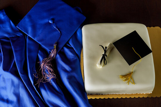 Top view of gown and graduation cap with cake for end of school.