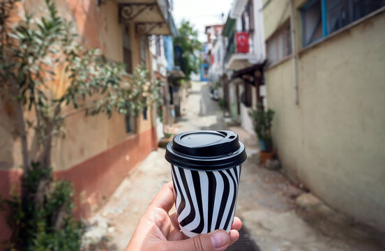 Paper Cup of morning coffee in the hand of a man walking through narrow streets of an ancient Turkish city
