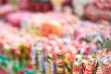 Fototapeta na wymiar Image out of focus, tasty colorful lollipops different shapes on the counter fair.
