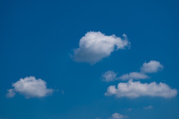 Naklejka na ściany i meble White clouds in shiny day blue background on sky