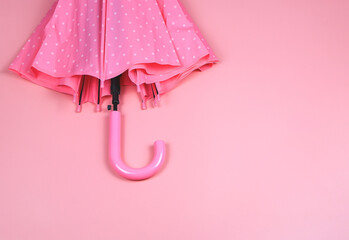 flat lay  of pink polka dot umbrella on pink background with copy space. rainy season concept.