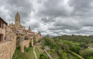 Fototapeta na wymiar Majestic view at the iconic Segovia city fortress and surrounding vegetation, spanish gothic building at the Segovia cathedral, tower