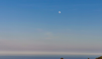 Luna piena di giorno sul mare vista dalle colline
