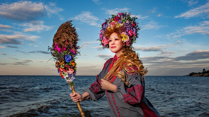 Ukrainian woman in national clothes against the background of the sea and clouds looks into the...