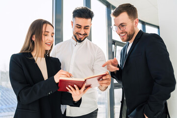 Three cheerful business people are standing in the office