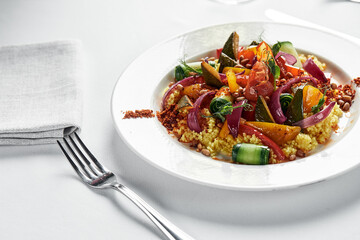 Vegetable stew with zucchini, tomatoes and bell pepper in a creamy sauce in a plate, on a white...