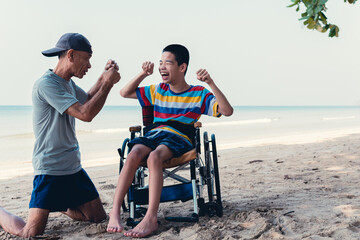 Disabled child on wheelchair playing sports for man with father on blue sea beach, Lifestyle of disability kid is a healthy and good mood in relaxing travel holidays with love in disabilities family.