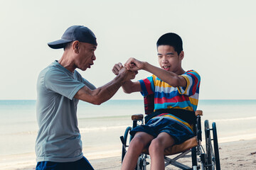 Disabled child on wheelchair playing sports for man with father on blue sea beach, Lifestyle of...