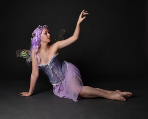 Full length portrait of a purple haired  girl wearing fantasy corset dress with fairy wings and...