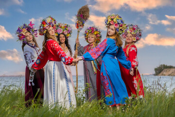 Ukrainian girls in national costumes lead a round dance on the seashore in summer