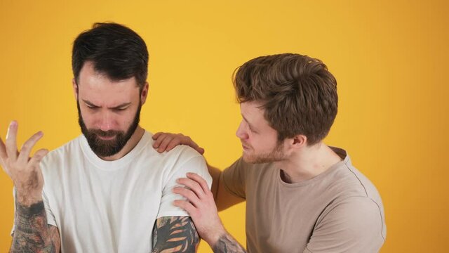 One friend calms the other standing isolated over yellow wall in the studio