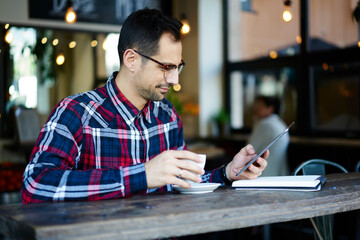 Positive man browsing tablet in cafe